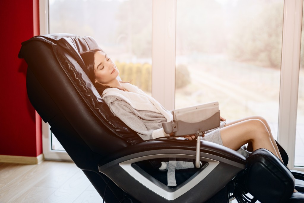 Young woman relaxing on the massaging chair at home