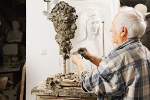 senior person doing an art piece made of mud