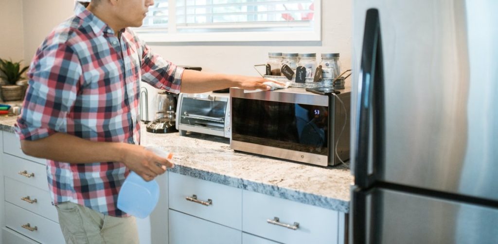 A Man Wiping a Microwave Oven